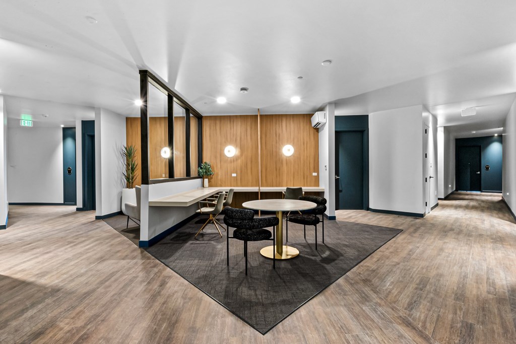 A modern office space with a wooden floor and a long table with chairs.