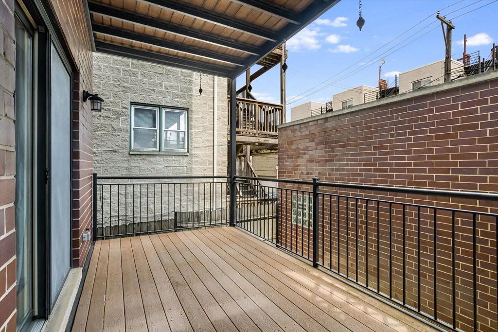A balcony with a wooden floor and a black railing.