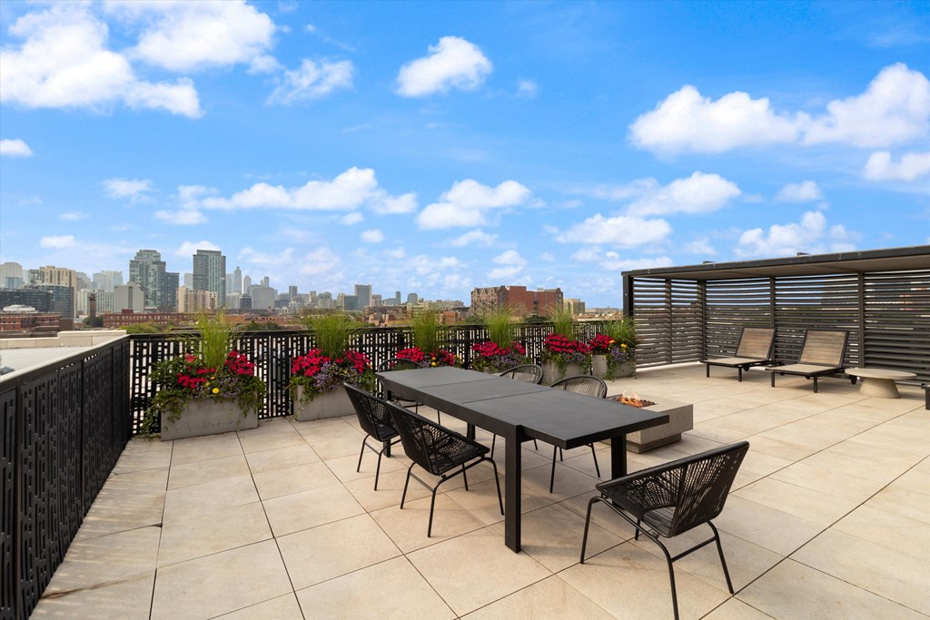 a roof deck with a table and chairs and a view of the city