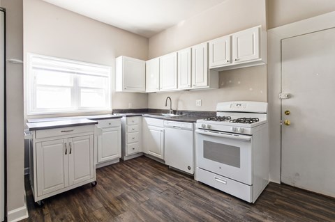A white kitchen with wood floors and white appliances.