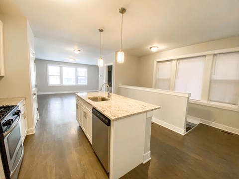 A kitchen with a marble countertop and wooden floors.