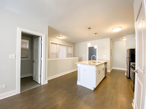A kitchen with white appliances and wooden floors.