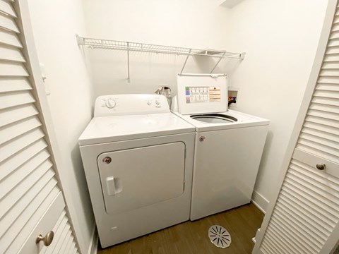 A small white laundry machine sits in a small room.
