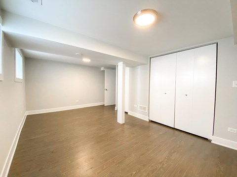 A room with white walls and wooden flooring with a white door.