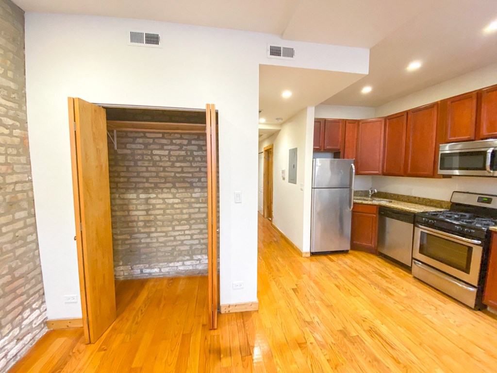 a kitchen with wood floors and a brick wall