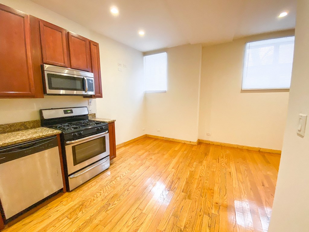 a kitchen with wood flooring and stainless steel appliances
