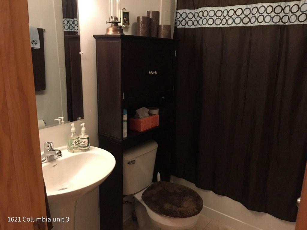 a bathroom with a black shower curtain and a toilet and sink
