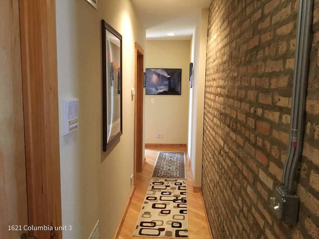 a hallway with a brick wall and a carpet on the floor