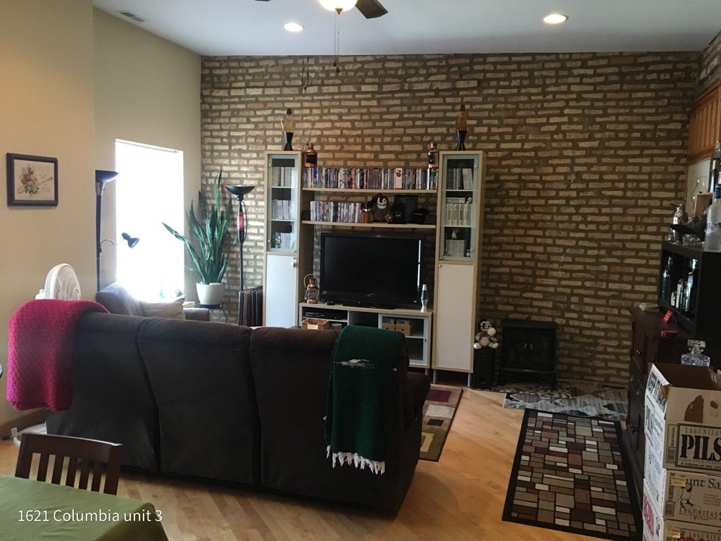 a living room with a black couch and a brick wall