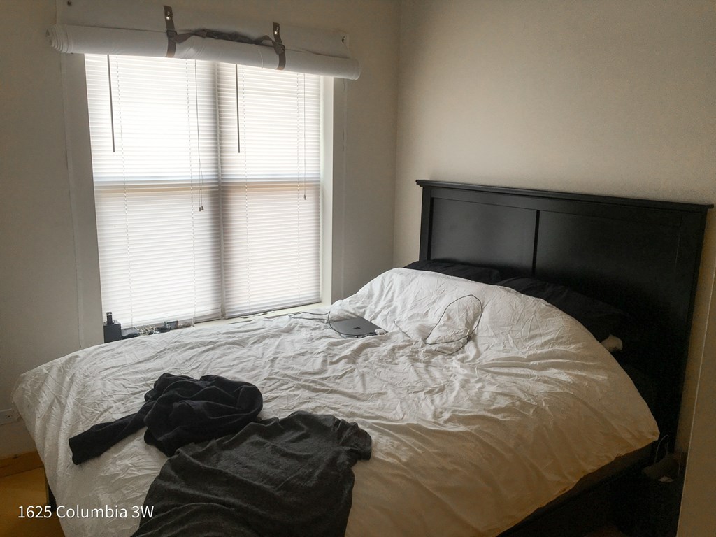 an unmade bed in a bedroom with a window