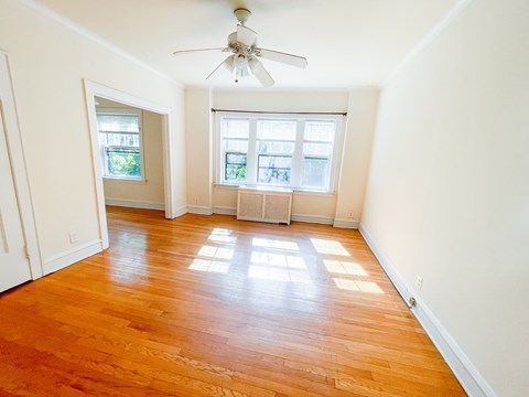 A room with a ceiling fan and wooden floors.