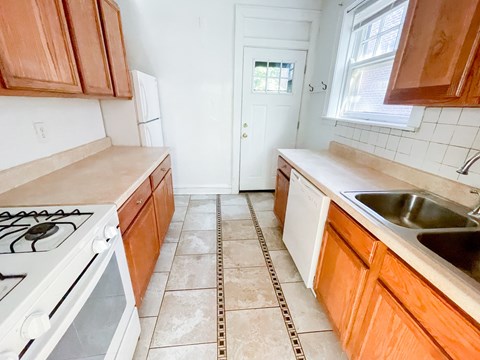 A kitchen with a white stove and wooden cabinets.