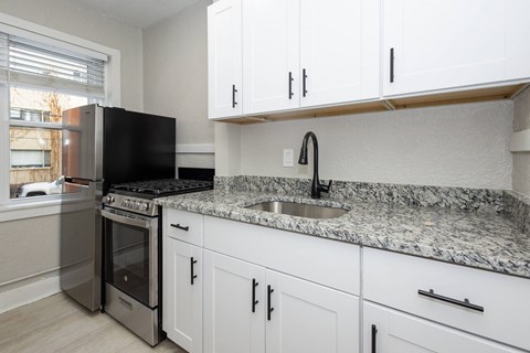 A kitchen with white cabinets and a granite countertop.