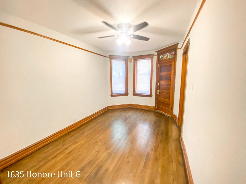 a empty living room with wood floors and a ceiling fan