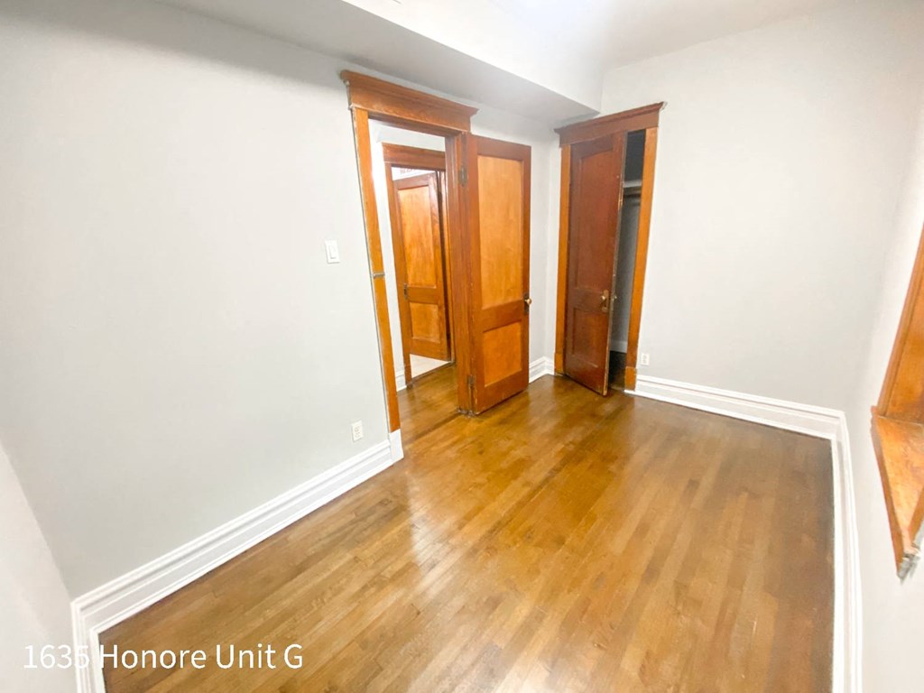 a room with wooden floors and white walls and three doors