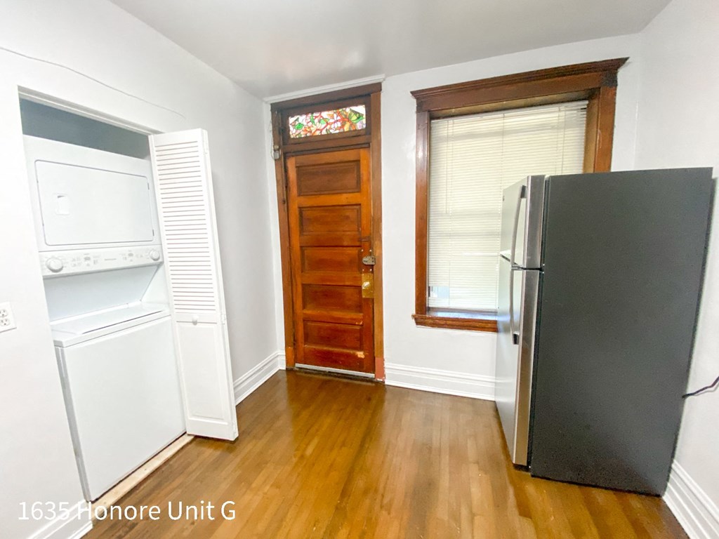 a small kitchen with a refrigerator and a door to a laundry room