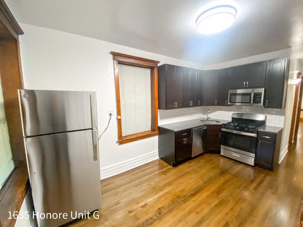 a kitchen with black cabinets and a stainless steel refrigerator