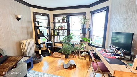 a living room with a desk and a tv in front of a window