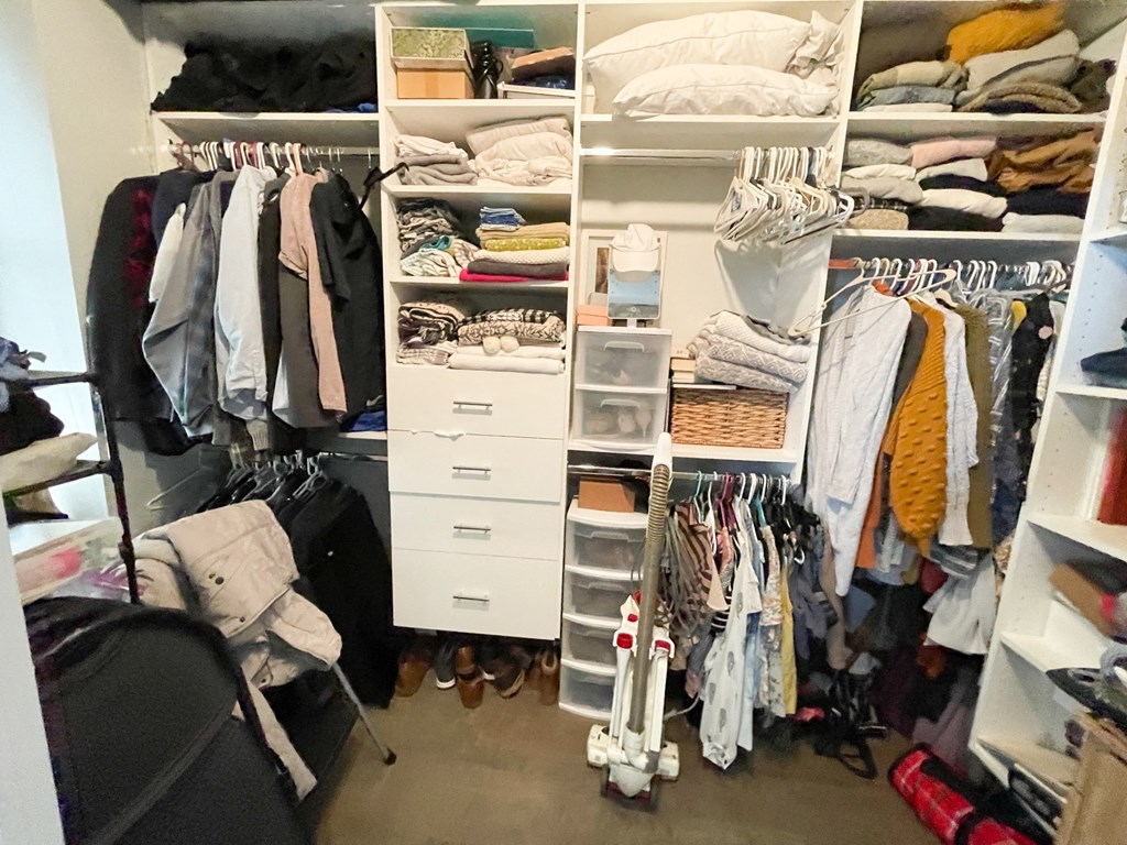 a closet with a lot of clothes and a dresser in it