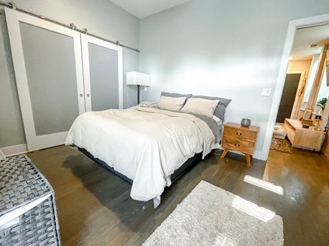 A bedroom with a bed, nightstand, and a rug.