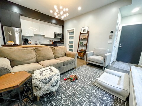 A living room with a grey sofa and a black and white rug.