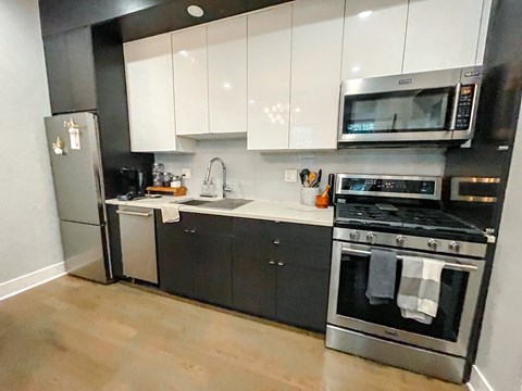 A modern kitchen with black cabinets and stainless steel appliances.
