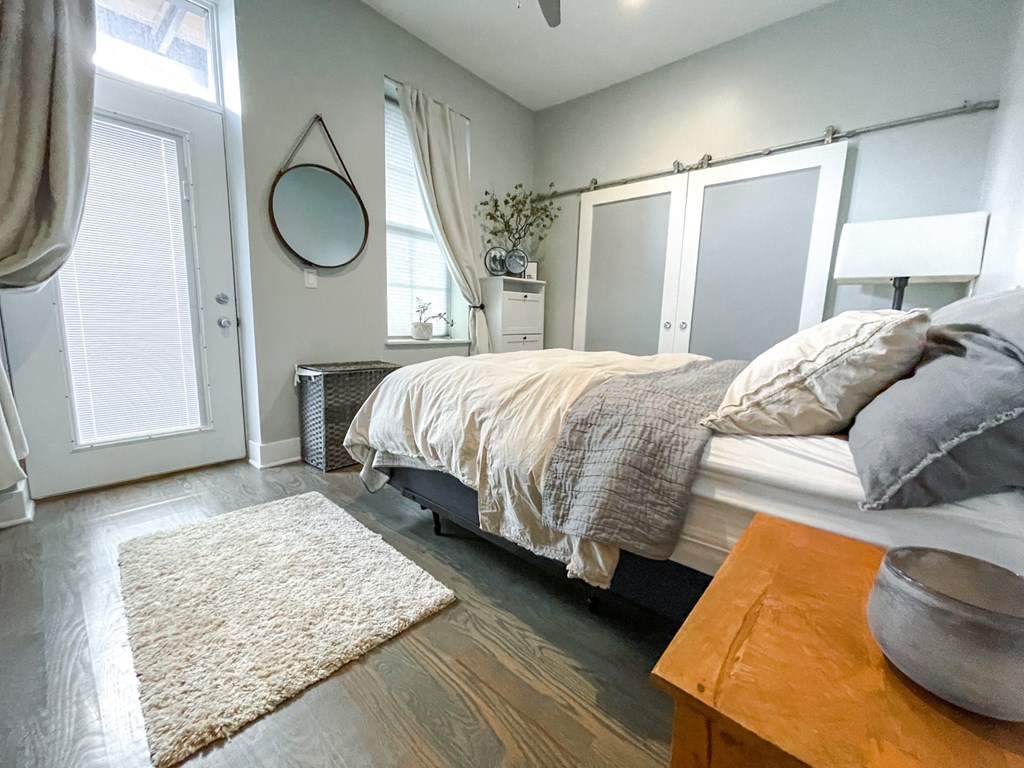 a bedroom with a bed and a rug and windows