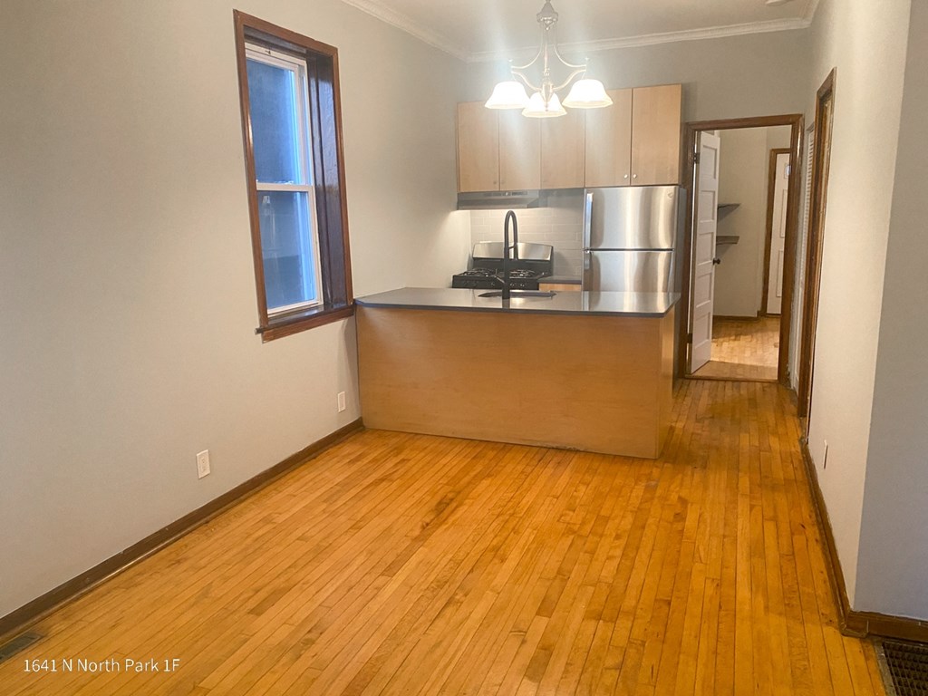 an empty living room with a kitchen in the background