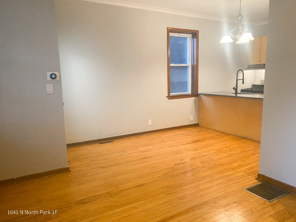 an empty living room with a kitchen in the background