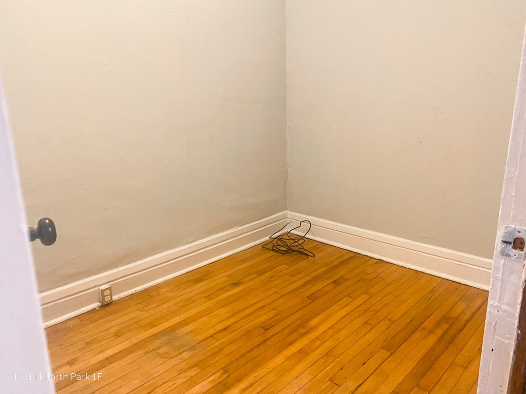 an empty room with hardwood floors and a door open