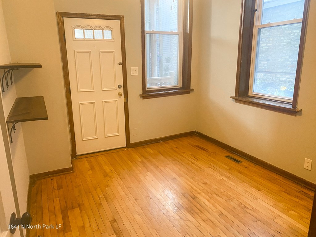 an empty room with a door and three windows