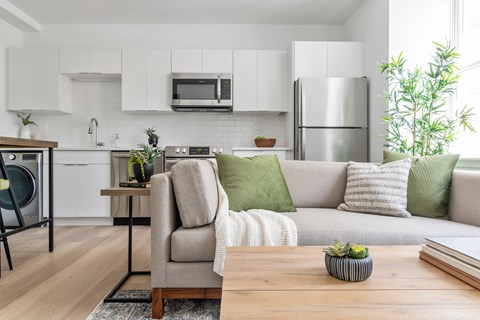 A modern kitchen with a grey couch and a wooden table.