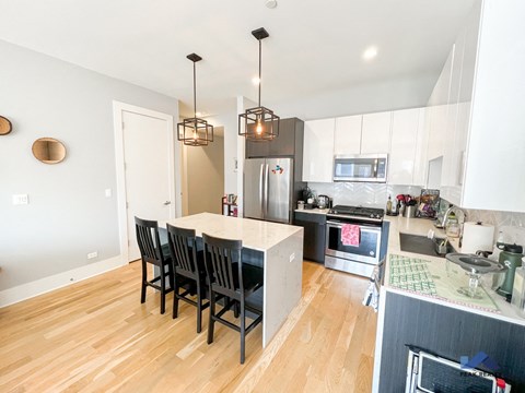 the kitchen and dining area of a house with white cabinets and a wooden floor