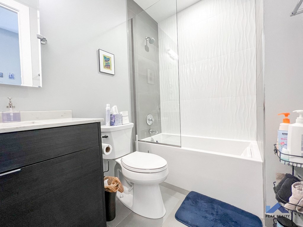 a bathroom with a white toilet next to a white bathtub