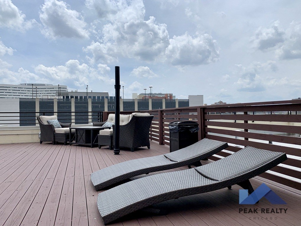 a roof top deck with lounge chairs and a fire pit