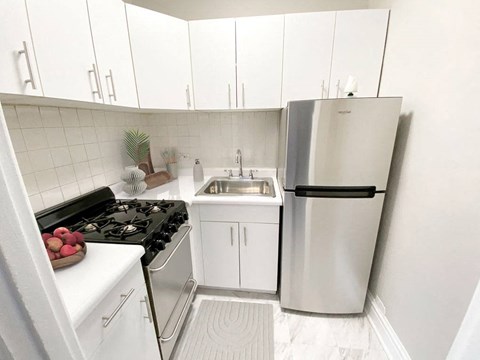 a white kitchen with a refrigerator and a sink