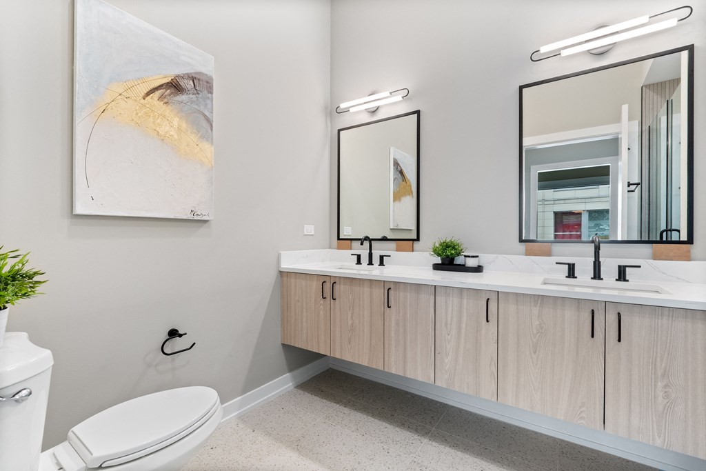 a bathroom with a toilet and two sinks and two mirrors