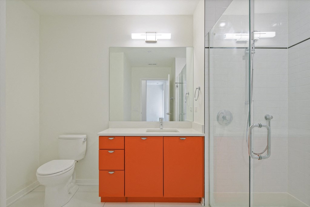 a bathroom with orange cabinets and a toilet and a shower