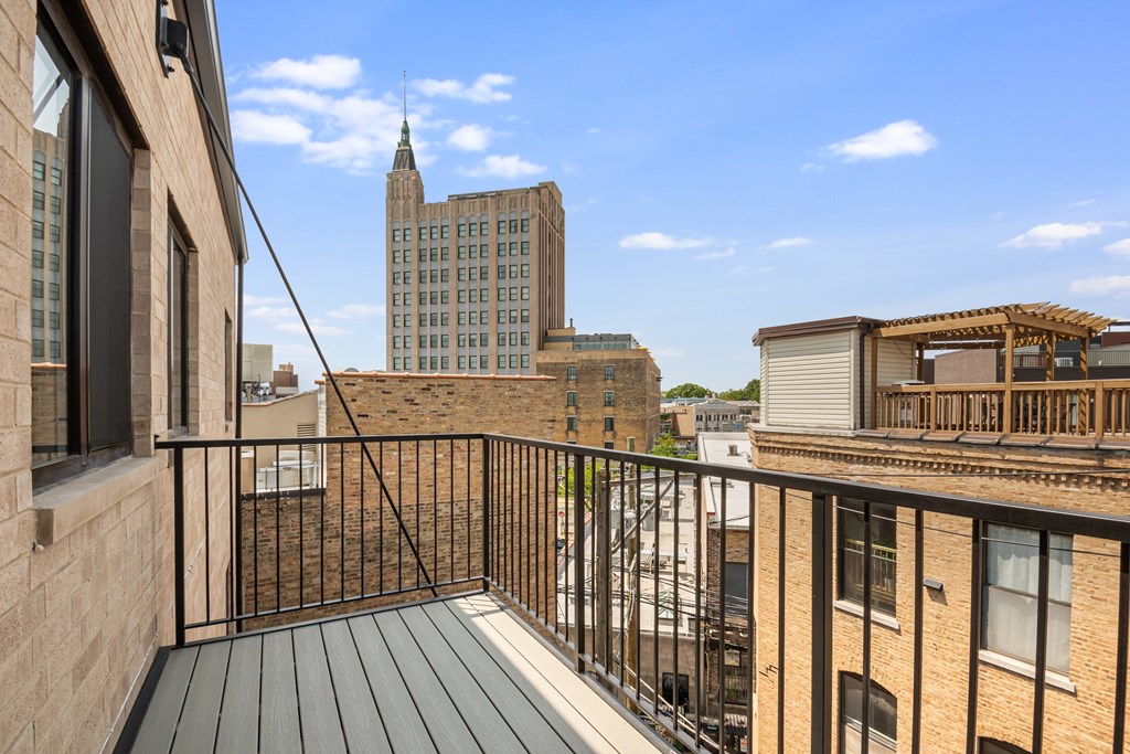 A balcony with a black railing and a view of a cityscape.
