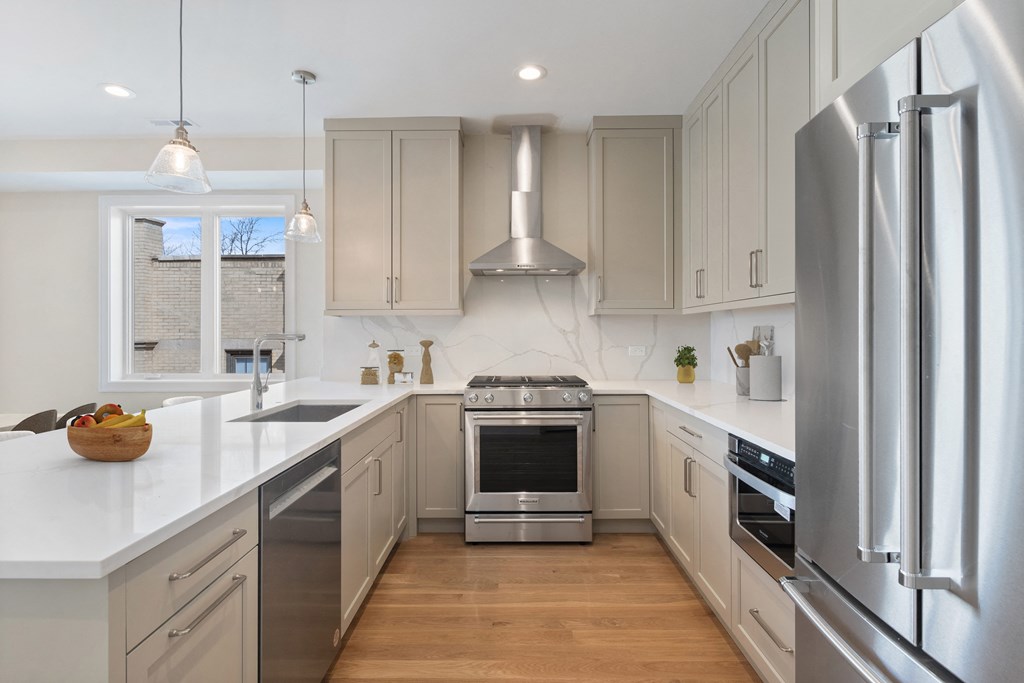 a white kitchen with stainless steel appliances and white counter tops