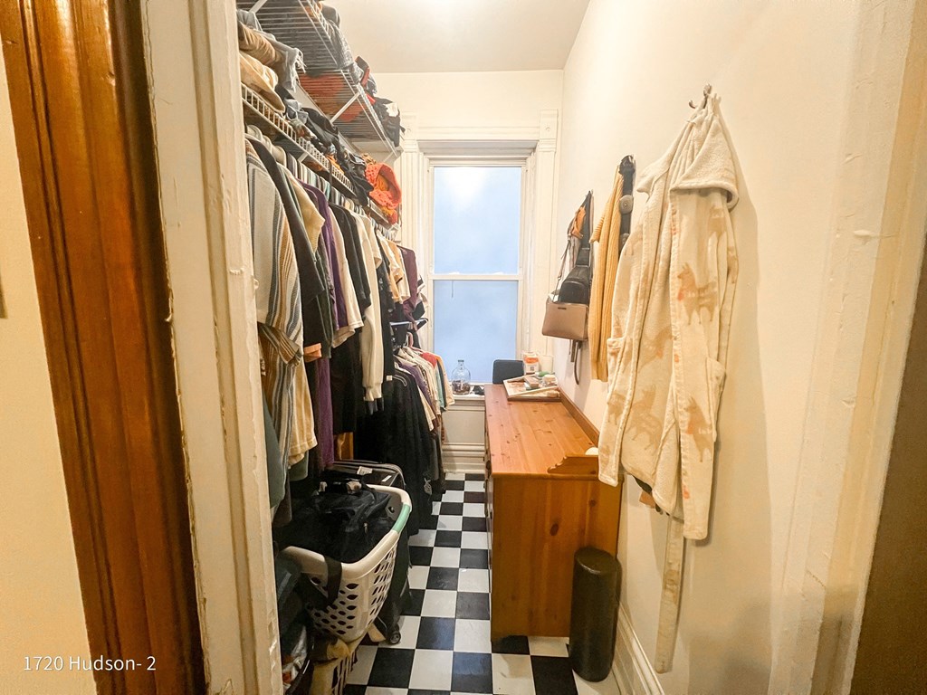 a walk in closet filled with clothes and a window