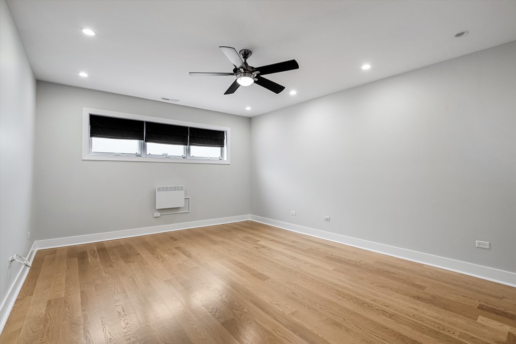 A room with a ceiling fan and wooden flooring.