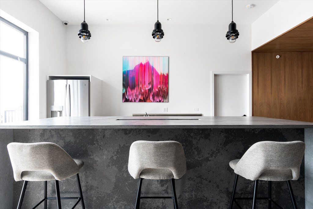 a kitchen with white walls and a large island with three stools in front of it