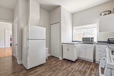 A white kitchen with wood floors and white appliances.