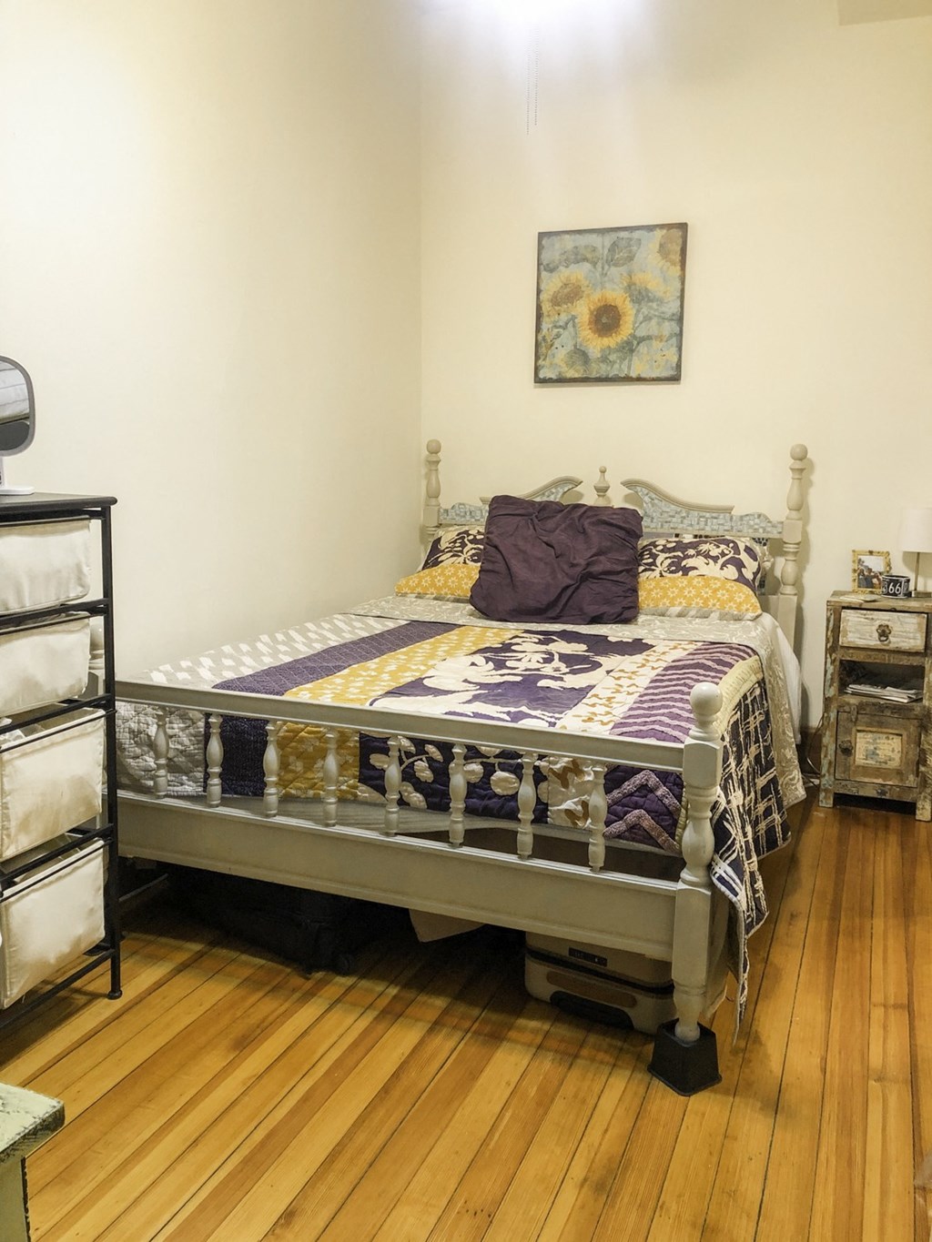 a bedroom with a bed in a room with a wooden floor