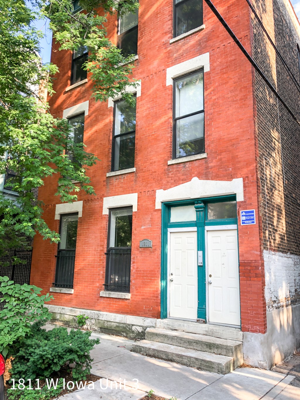 a red brick building with a white door and a green door