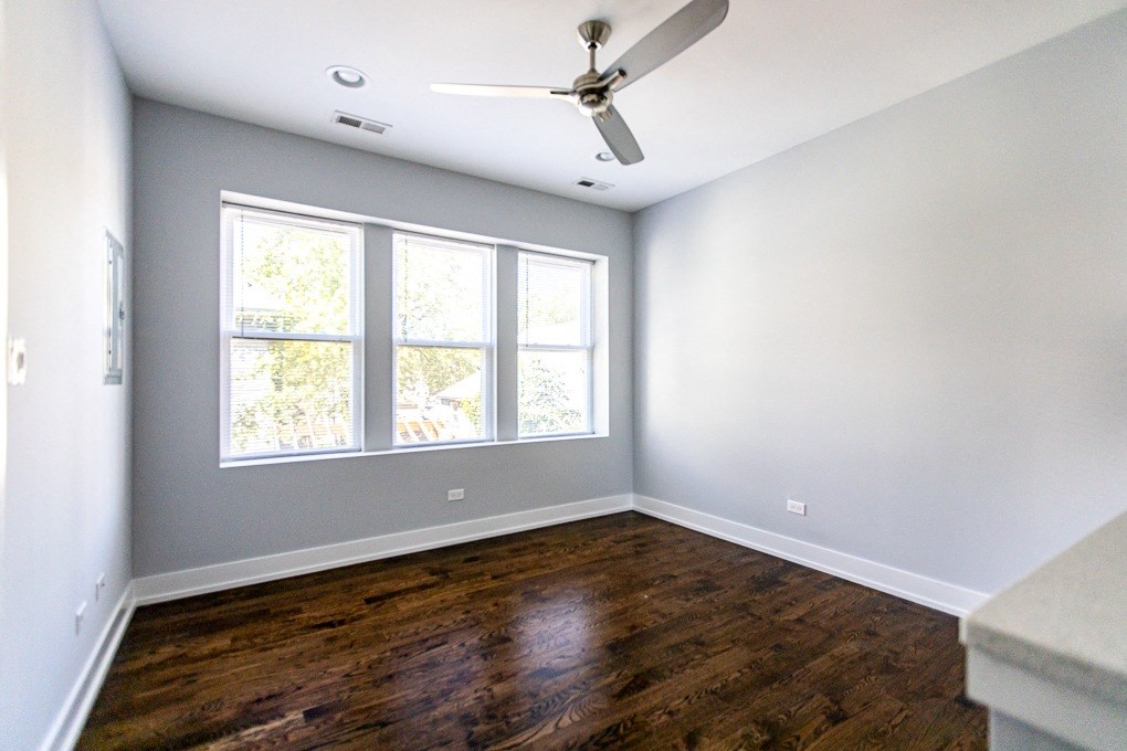 an empty living room with wood floors and a ceiling fan
