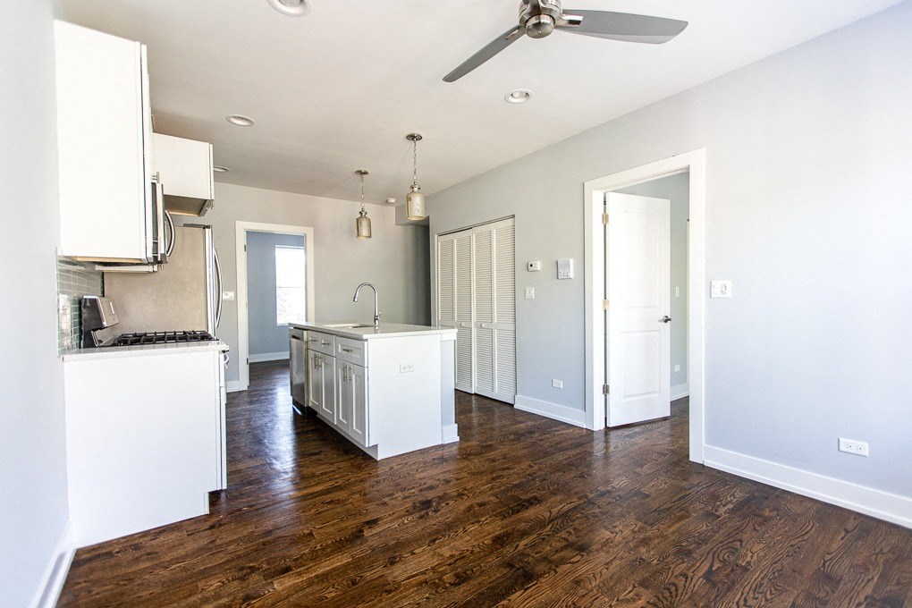 an empty kitchen with white cabinets and a wood floor