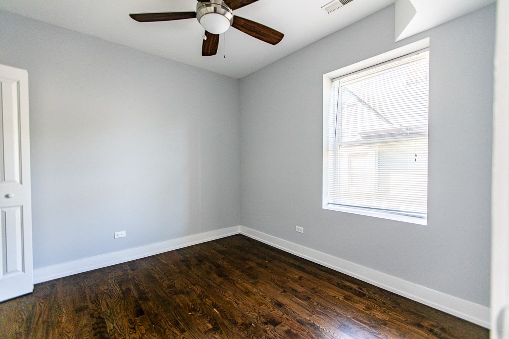 an empty room with wooden floors and a ceiling fan