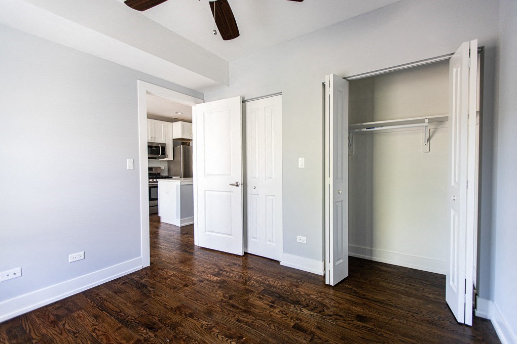 an empty bedroom with a sliding closet door and a kitchen